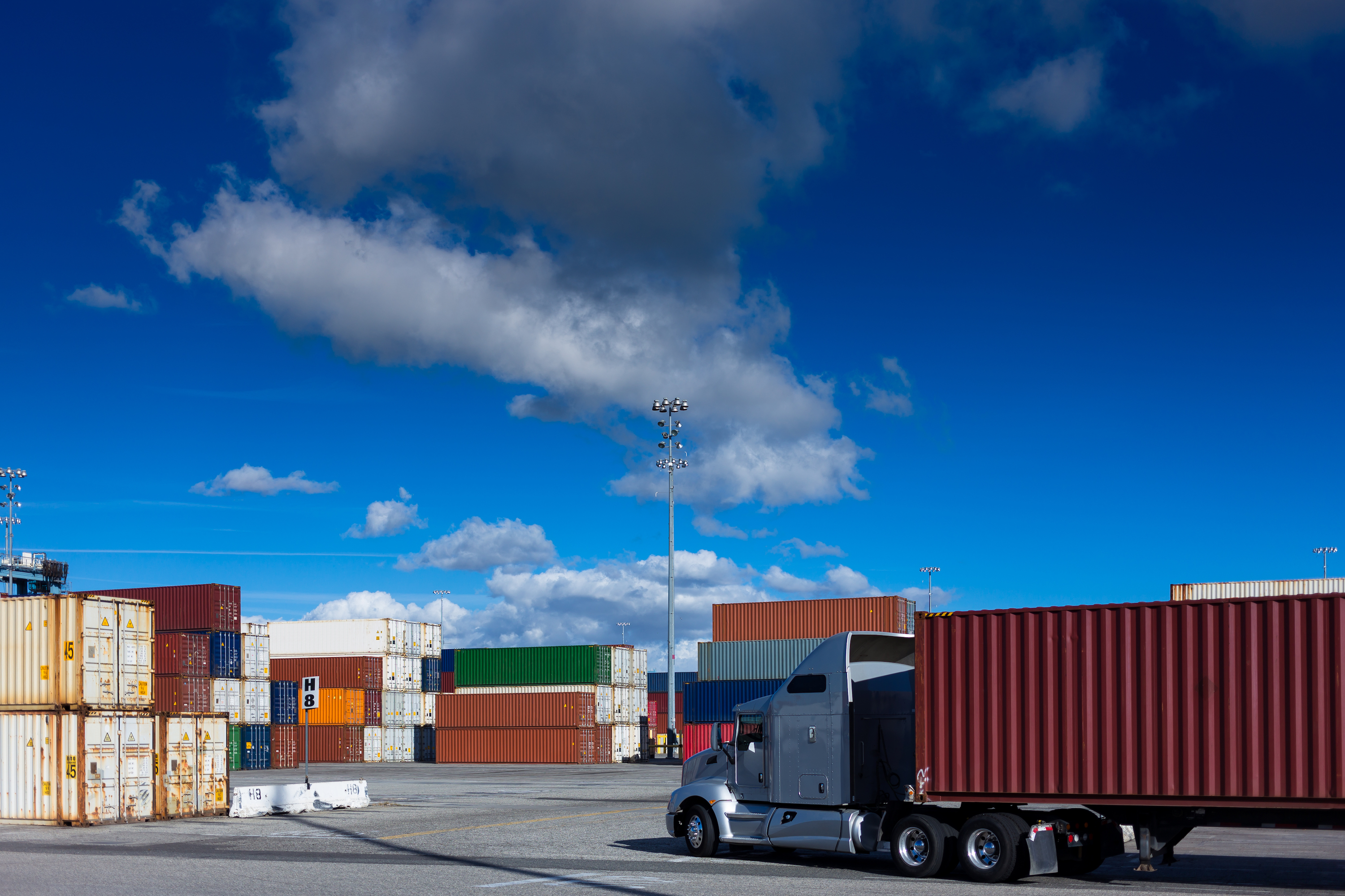 A semi truck hauling a shipping container at a shipping facility.